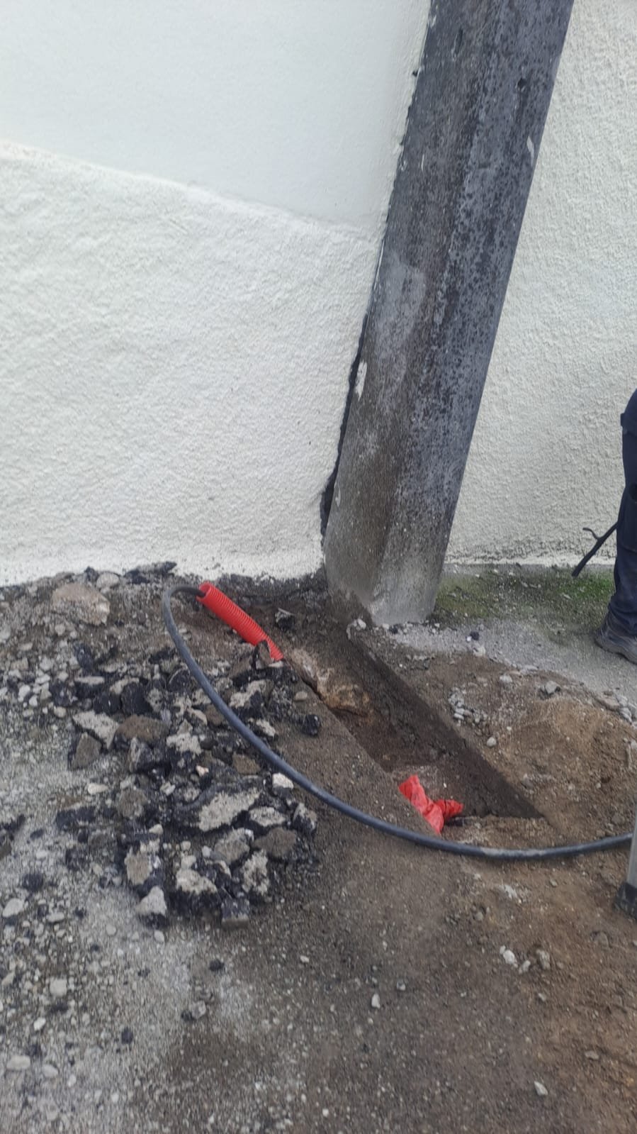 Conduit laid in the trench, running toward the base of the building